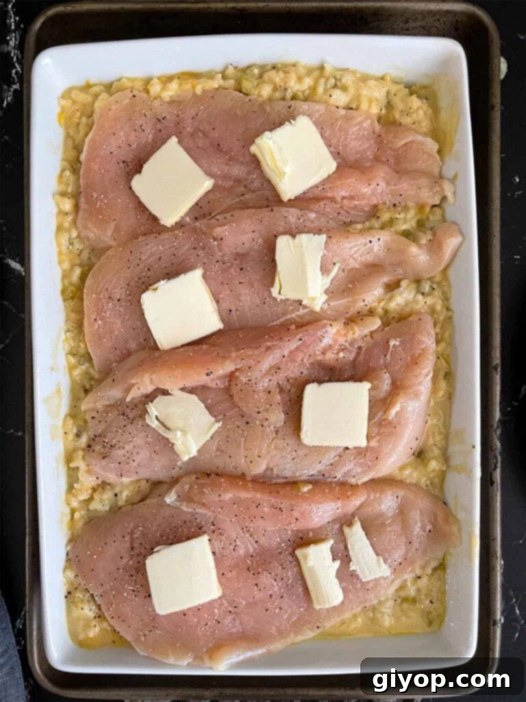 Chicken breast halves topped with pat of butter on top of the rice mixture.