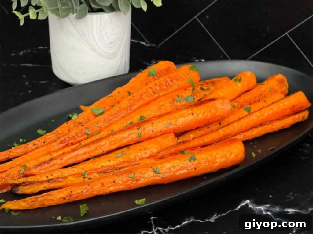 Roasted whole carrots on a dark plate garnished with chopped parsley.