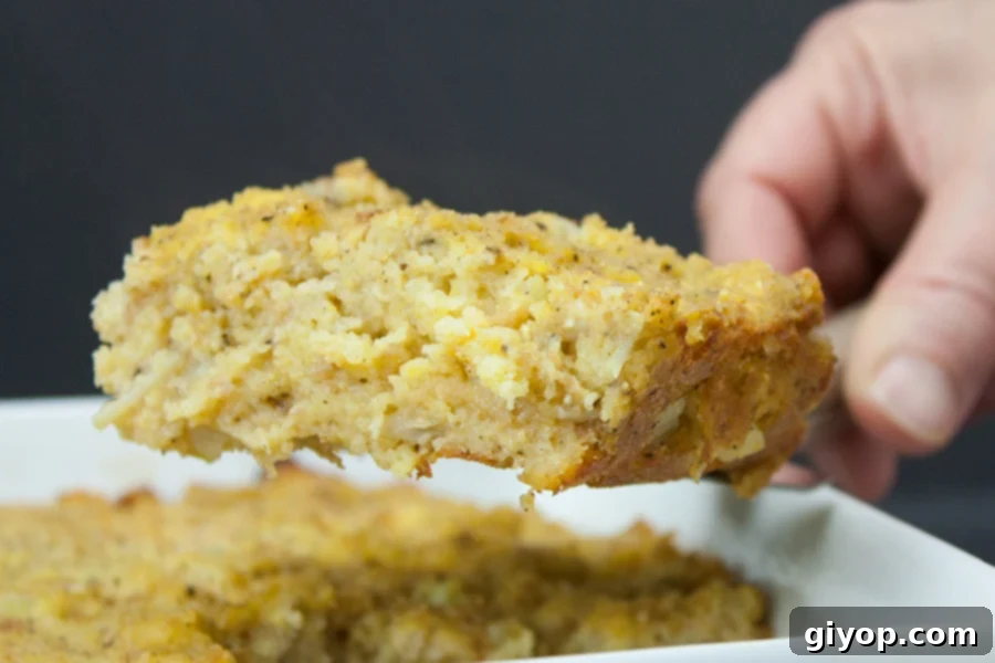 A serving of Southern Cornbread Dressing being scooped from the pan, highlighting its texture and steam.