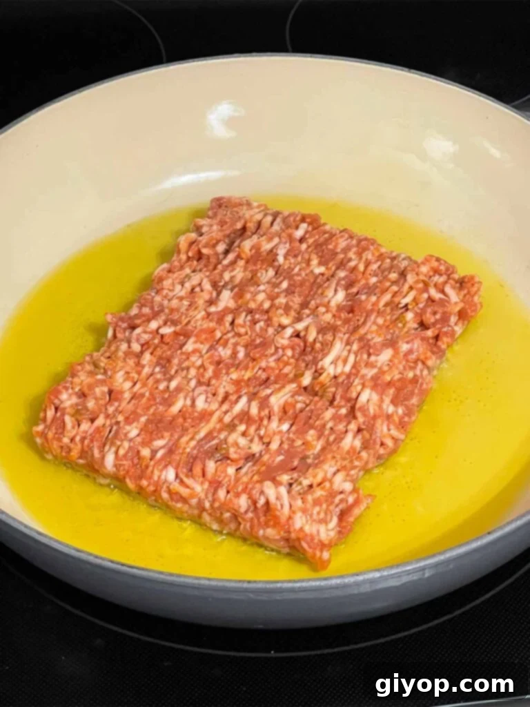 Ground sausage in olive oil in a skillet.