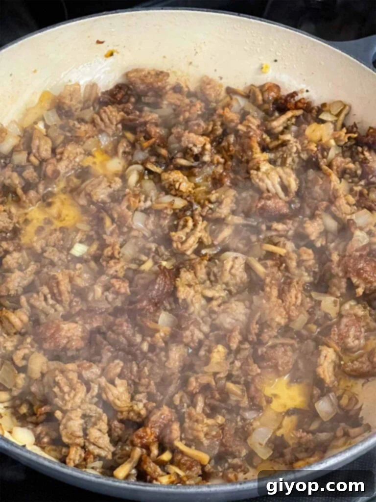 White wine being added to Italian sausage in a skillet.