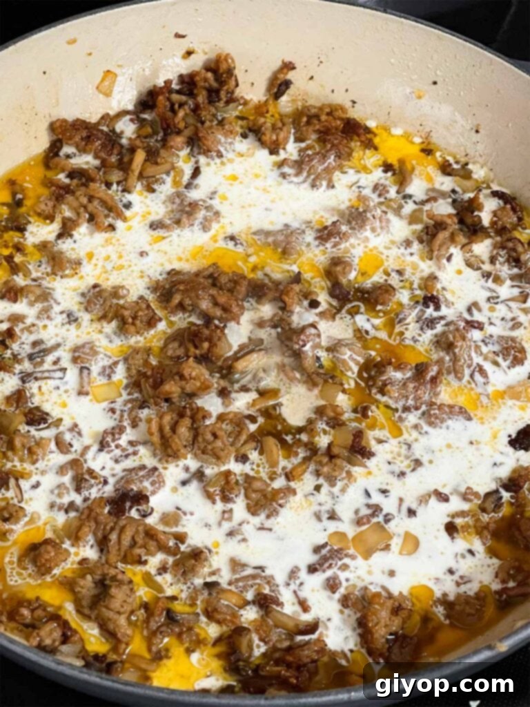 Adding heavy cream to the Pasta alla Norcina sauce.