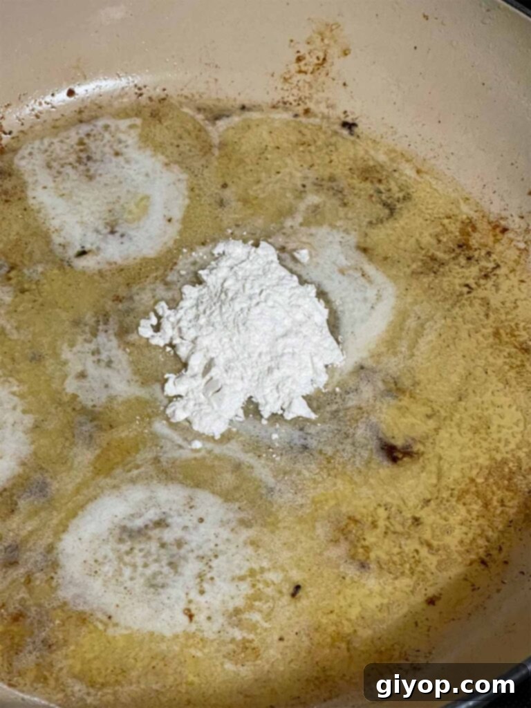 Melted butter, minced garlic, and flour creating a fragrant roux in a skillet, ready for the liquid.
