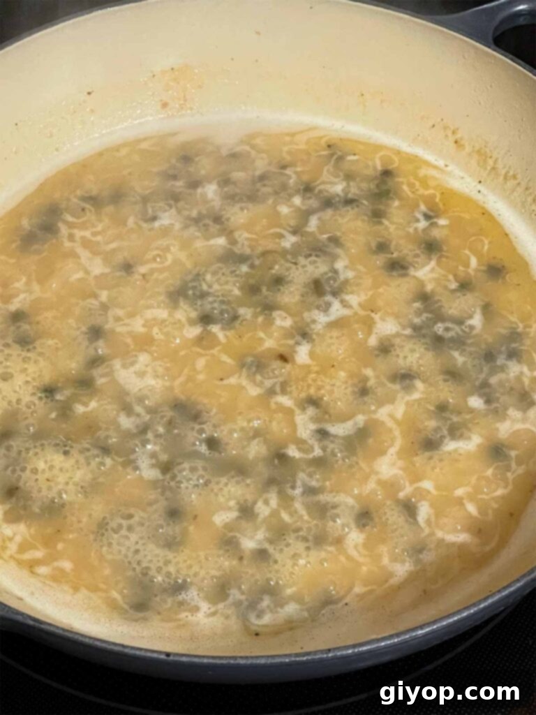 A vibrant piccata sauce simmering in a skillet, filled with capers and lemon slices, thickening beautifully.