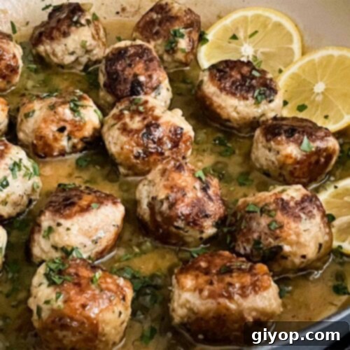 Chicken Piccata Meatballs in a skillet, bathed in lemon caper sauce.