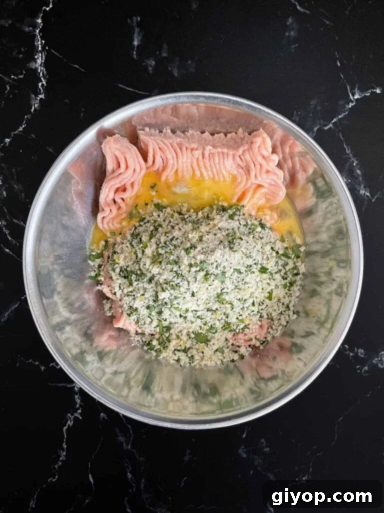 Close-up of the chicken piccata meatball mixture, showing the finely chopped herbs and spices incorporated.