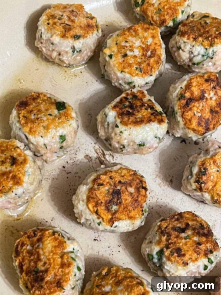 Several chicken piccata meatballs achieving a beautiful sear on all sides in a non-stick skillet.