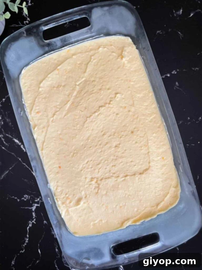Velvet Coconut Dream 9 The smooth coconut cream pudding mixture spread evenly over the cheesecake layer in a glass baking pan, completing the third layer.