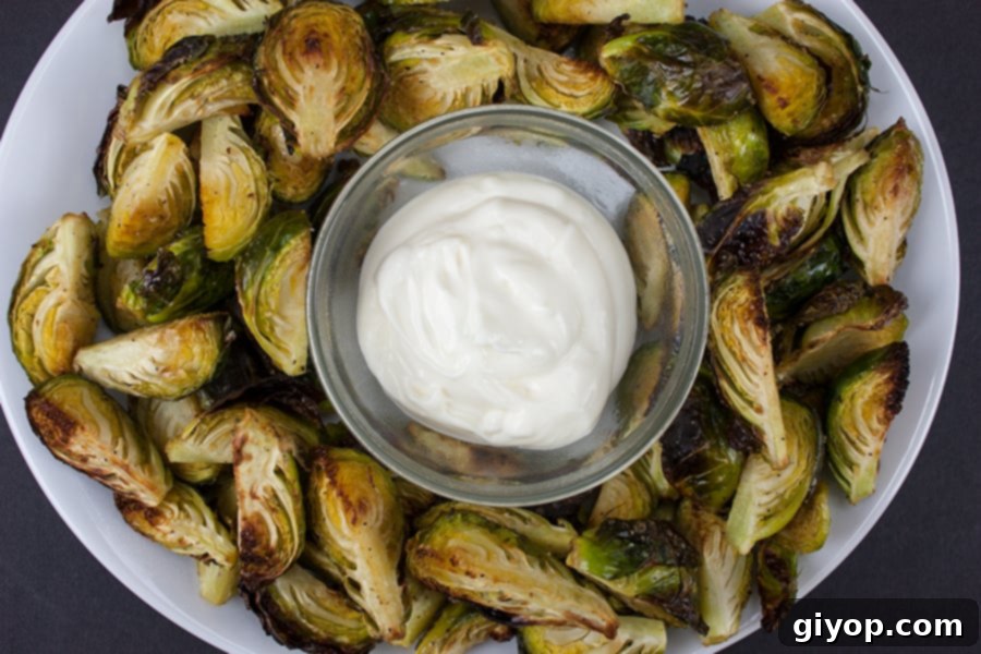 Roasted brussels sprouts with aioli in a glass ramekin, presented as a holiday appetizer.