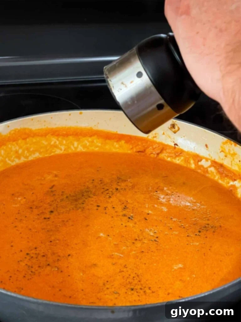Seasoning the vodka sauce with salt and pepper.