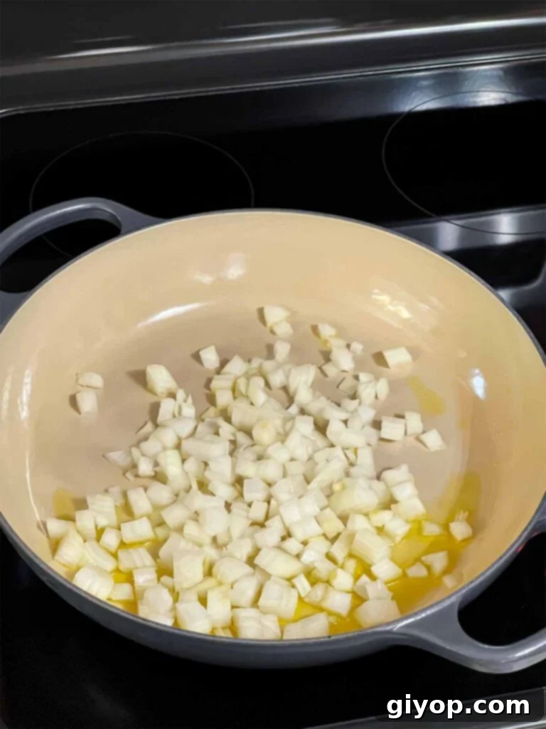 Onions cooking in a skillet, becoming soft and translucent.