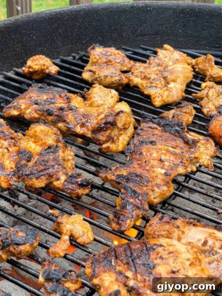 Chicken thighs cooking on a kettle grill.