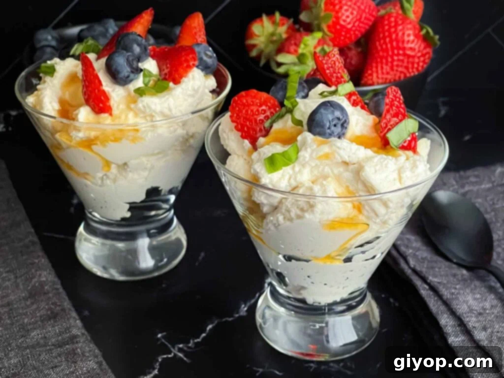 Ricotta mousse in a stemless martini glass garnished with strawberries, blueberries, basil, and honey.