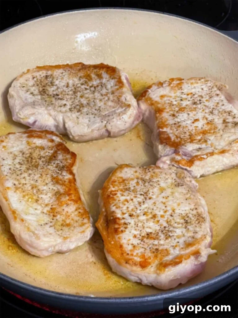 Browned pork chops in a skillet.