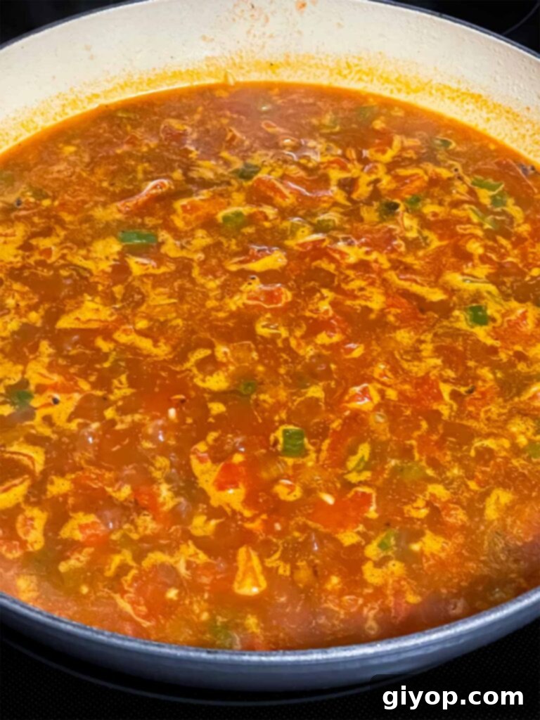Spanish rice ingredients simmering in a skillet.