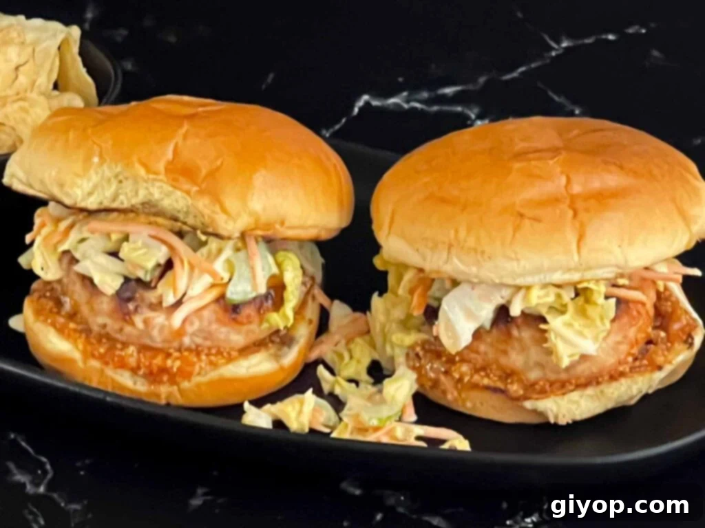 Grilled Carolina chicken burgers on a black plate, ready to be served.