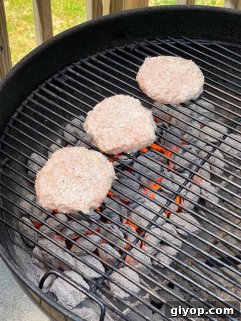 Chicken burgers cooking on a charcoal grill, showing direct and indirect heat zones.