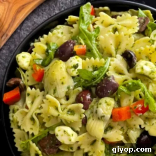 Zesty Mediterranean Pasta with Garden Herb Dressing 9 Mediterranean pasta salad in a dark bowl on a dark surface, garnished with fresh herbs and a drizzle of olive oil.