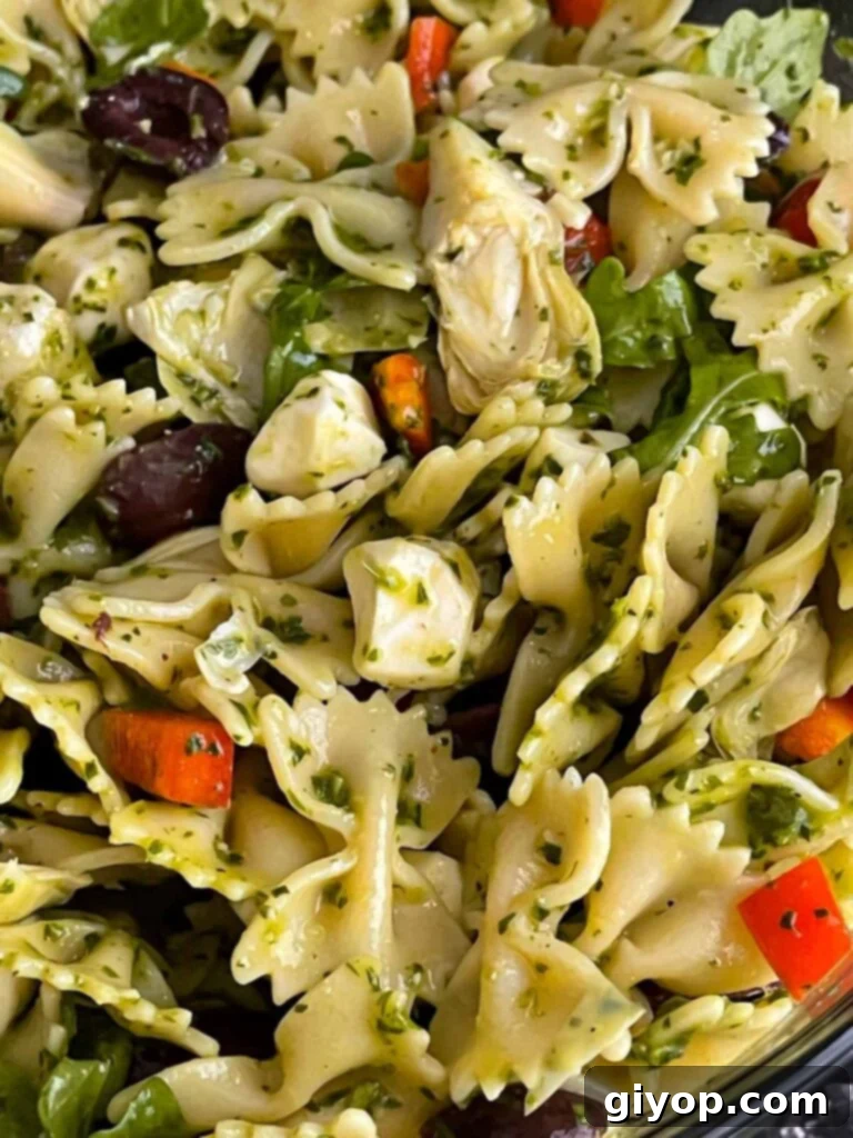 Zesty Mediterranean Pasta with Garden Herb Dressing 8 A large glass bowl filled with colorful Mediterranean pasta salad, mixed and ready to serve, showcasing the vibrant vegetables and pasta.