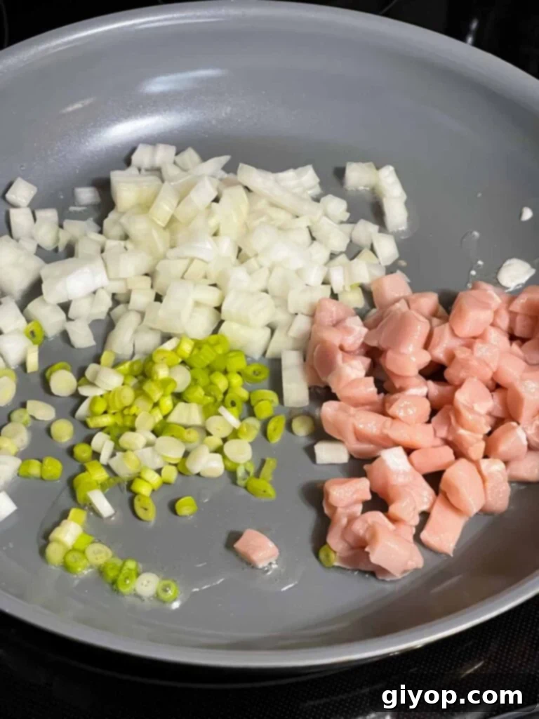 Onions, green onions, and pork in a skillet.