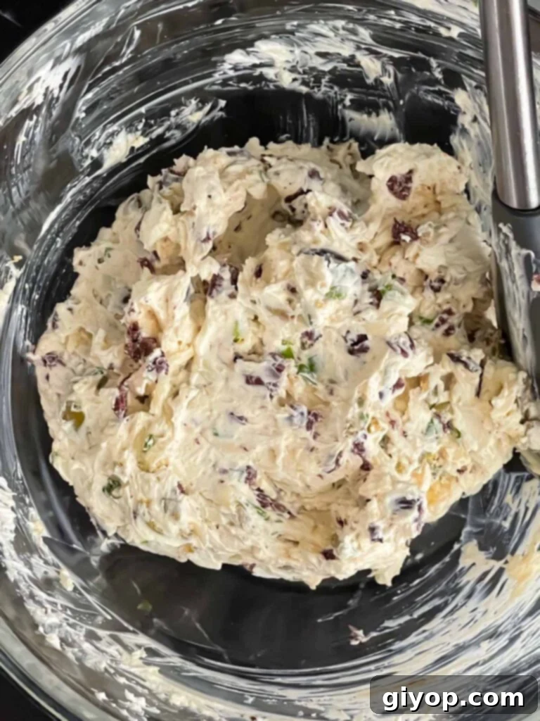Mediterranean Olive Cheese Ball 5 All the olive cheese ball ingredients blended together in a glass mixing bowl, showcasing a rich, textured mixture.