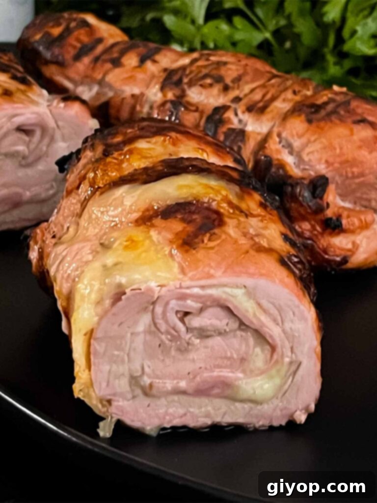 Grilled Mojo Pork Roulade 11 Sliced Grilled Cuban Pork Tenderloin medallions on a black plate, ready to serve.