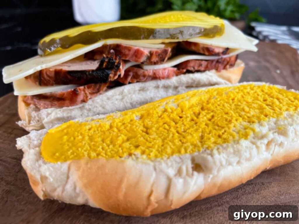 Grilled Mojo Pork Roulade 13 Assembling a Grilled Cuban Pork Tenderloin sandwich with layers of meat and cheese.