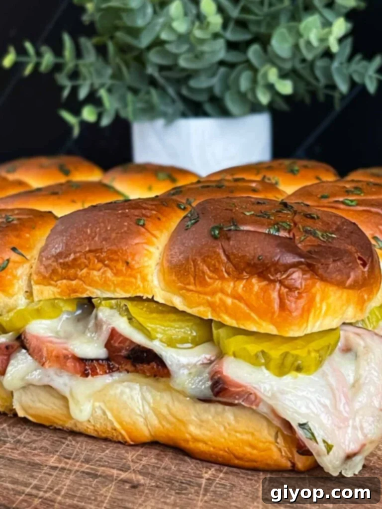 Freshly baked roll-cut pork tenderloin Cuban sliders with melted cheese.