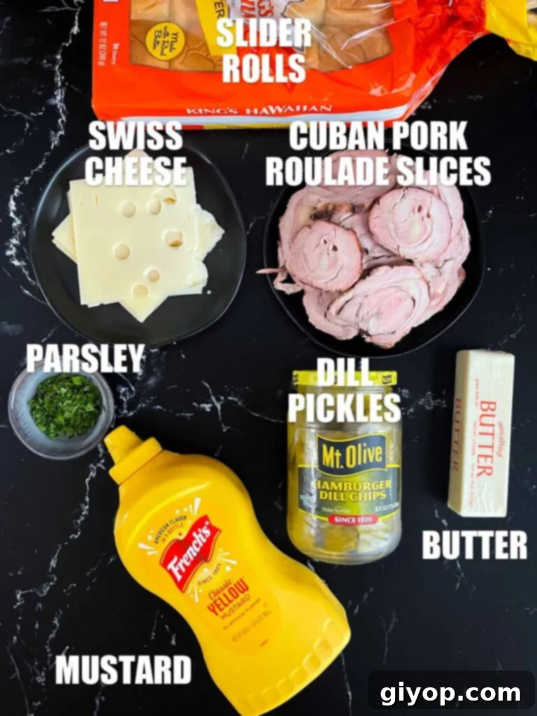 A selection of ingredients for making roll-cut pork tenderloin Cuban sliders, including rolls, cheese, pickles, and mustard.