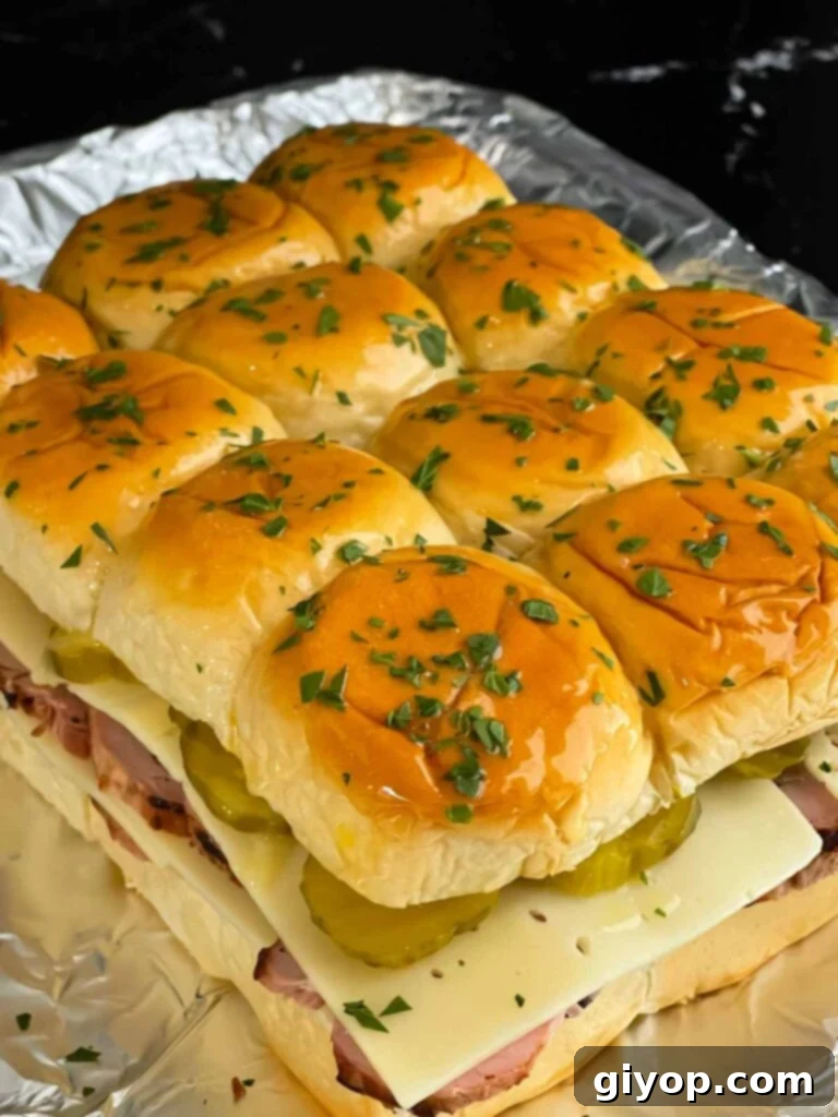 Cuban slider tops buttered and garnished with chopped parsley before baking.