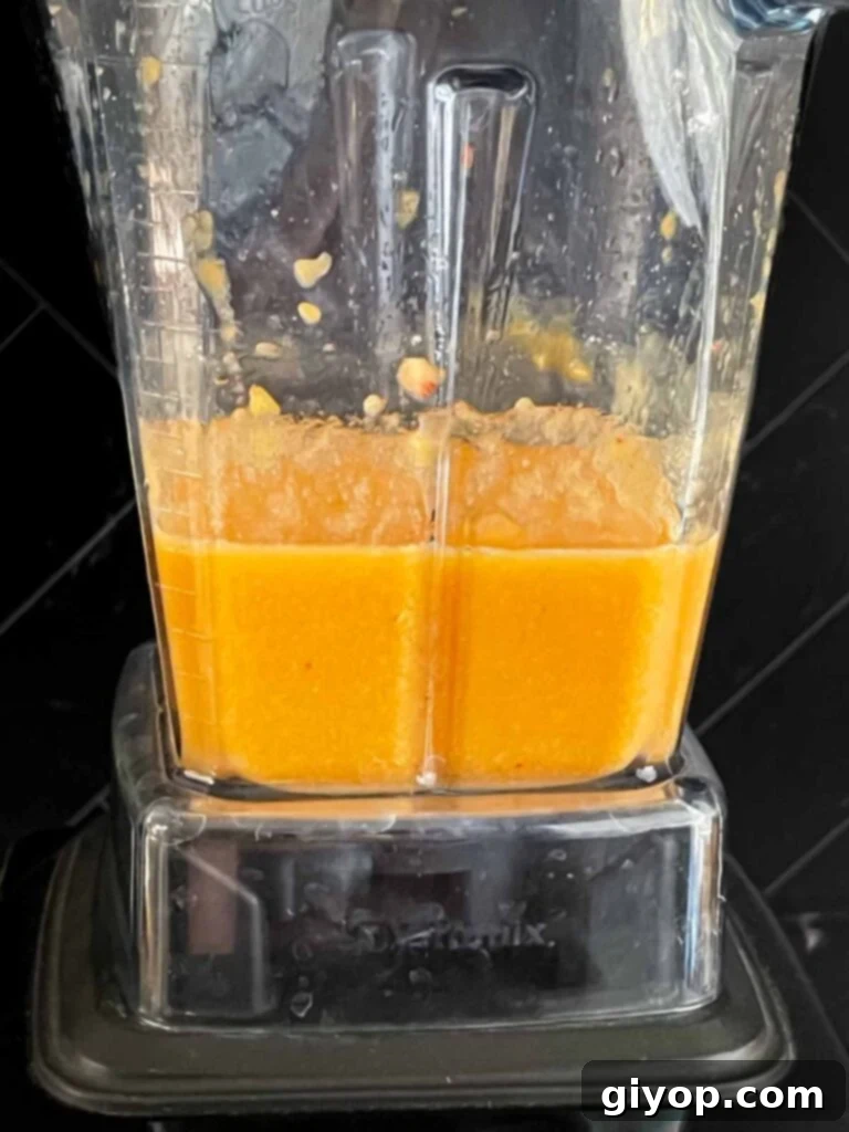 Fresh peach chunks being pureed in a blender, ready to be transformed into a concentrated flavor base for the cake.
