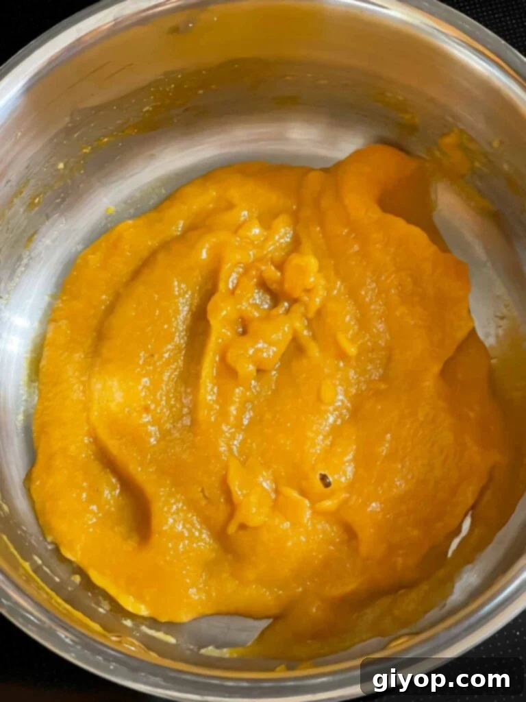 The peach puree simmering and reducing in a small saucepan, concentrating its natural sweetness and flavor.