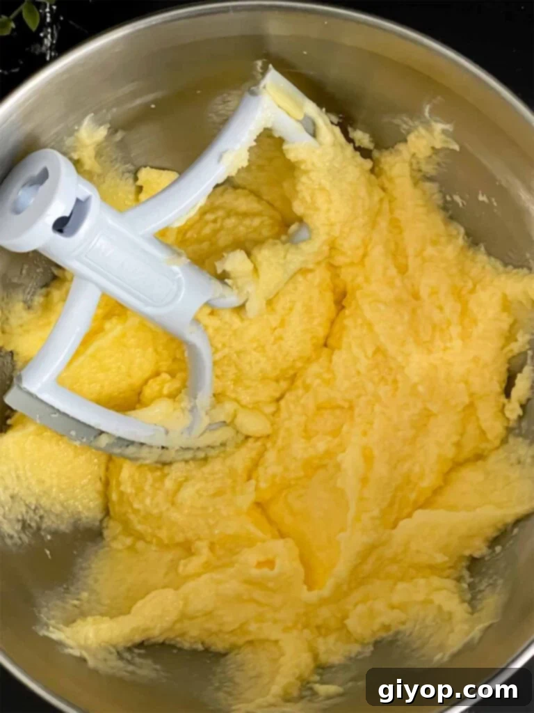 Eggs being incorporated into the peach pound cake batter, ensuring a smooth and cohesive mixture.