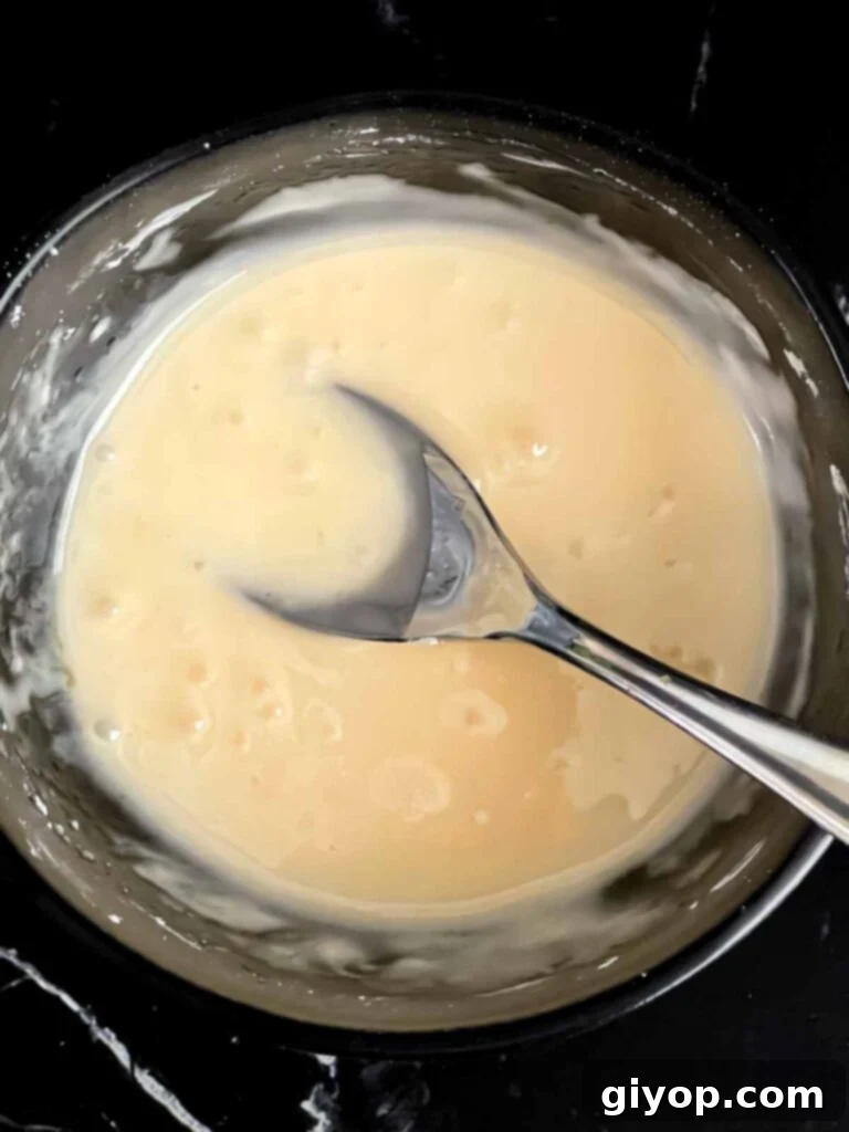 A small dark bowl holds the freshly mixed peach glaze, smooth and ready to be drizzled over the cooled pound cake.