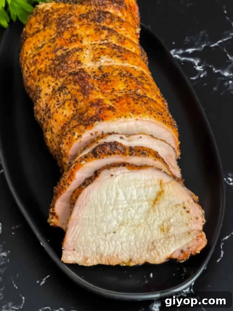 Texan Pit Smoked Pork Loin 11 A Texas style smoked pork loin on a black serving plate with some slices.