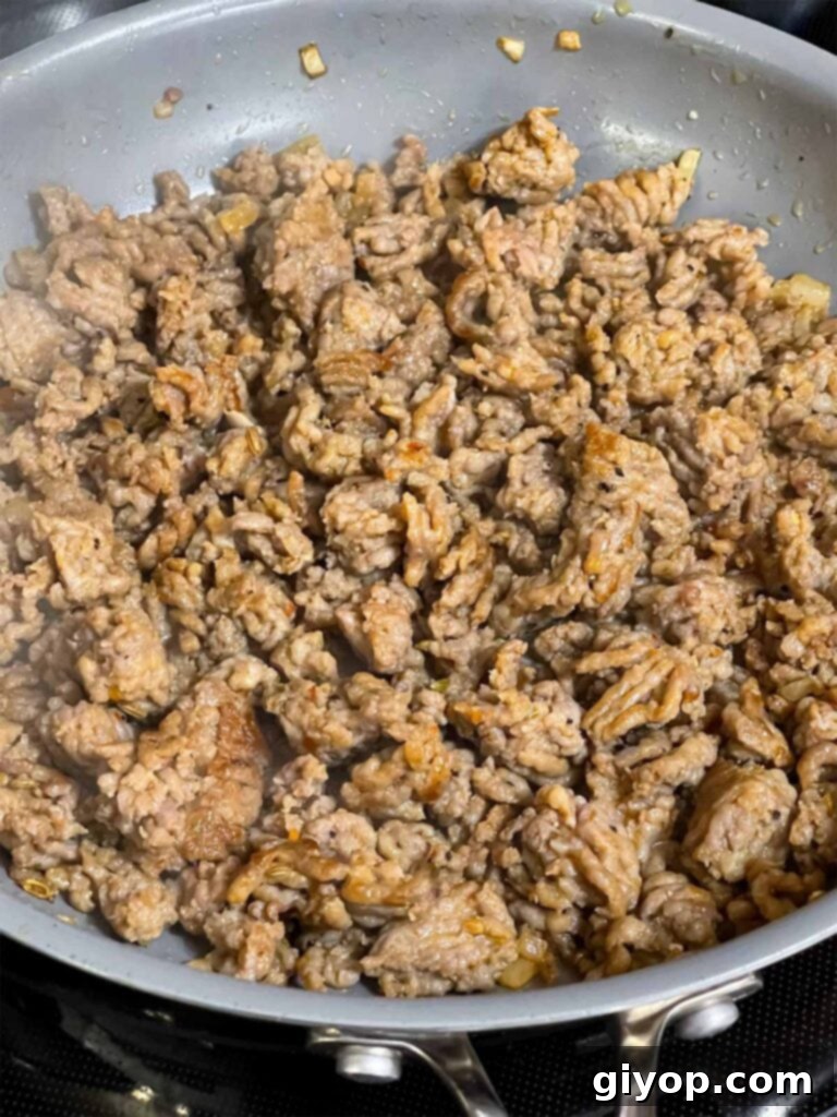 Fully cooked Italian sausage, broken into small pieces, in a skillet.