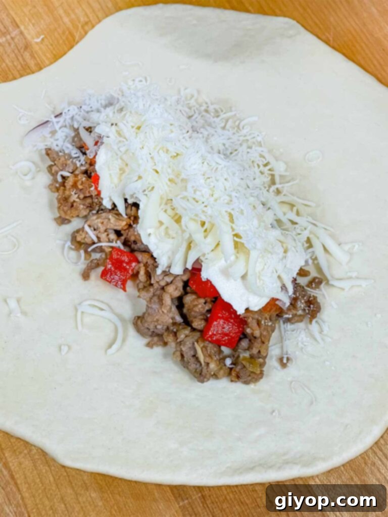 A calzone being assembled with the final cheese layers.