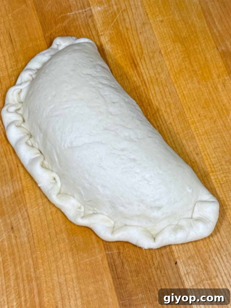 An Italian calzone, sealed and crimped, ready for baking.