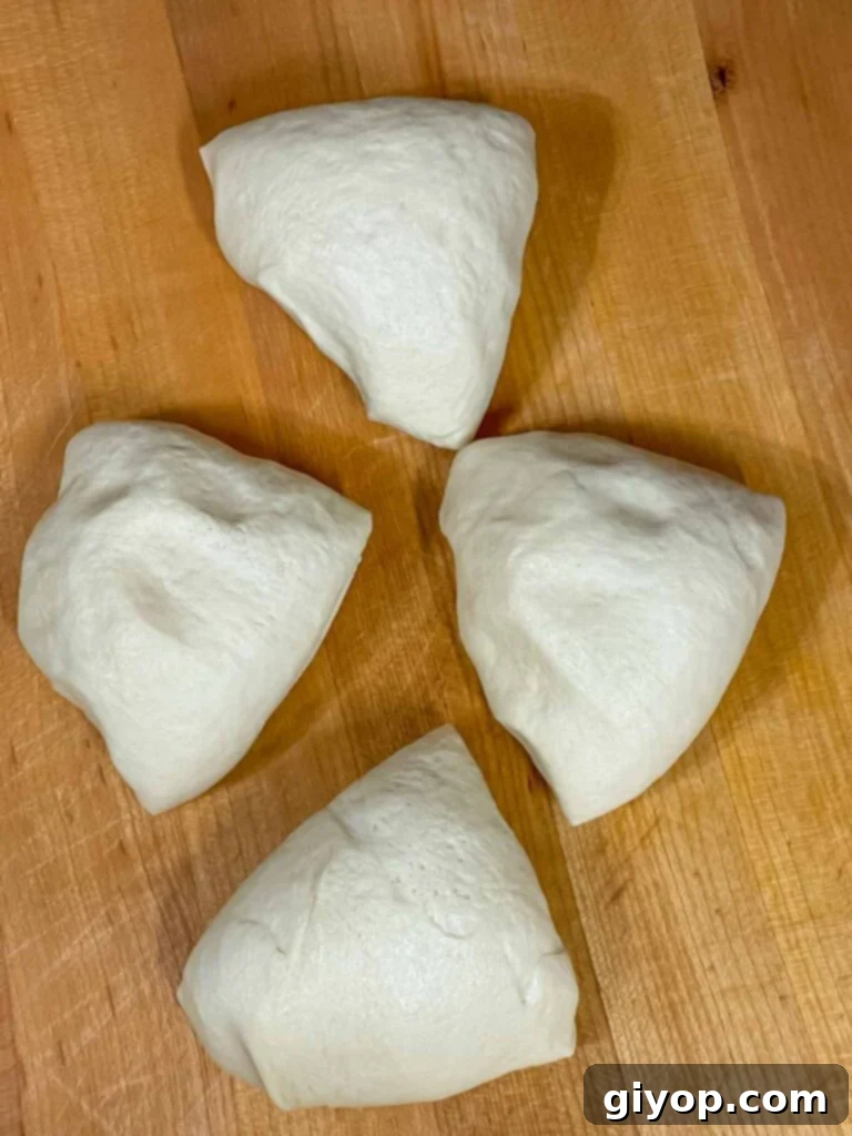 Calzone dough divided into four equal portions on a floured surface.