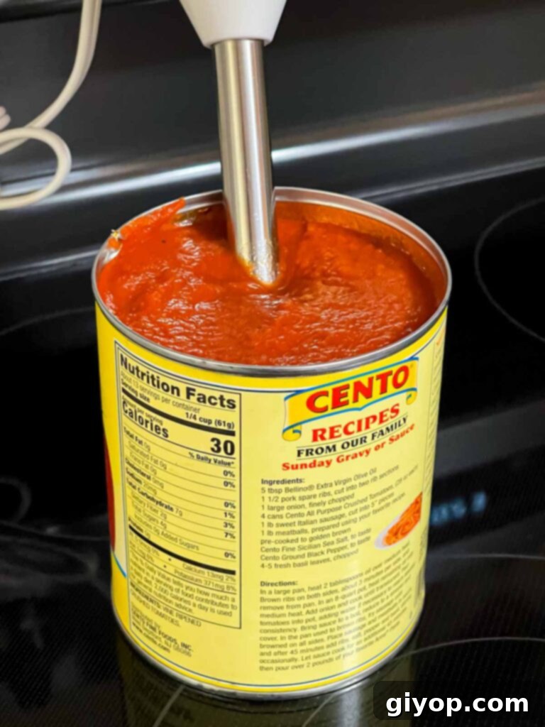 Blending crushed tomatoes and seasonings with an immersion blender directly in the can.