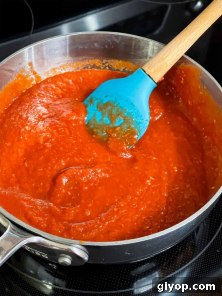 Homemade calzone dipping sauce simmering gently in a saucepan.