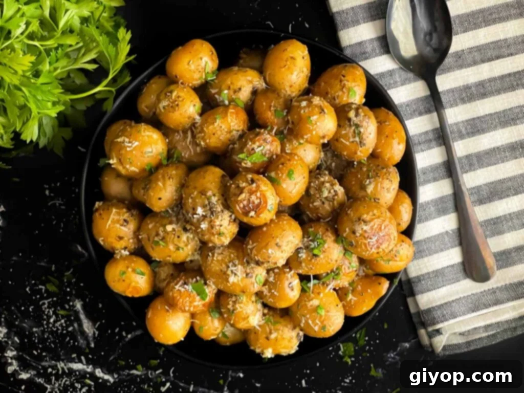 Slow cooker garlic parmesan potatoes in a dark bowl garnished with parsley and parmesan cheese.