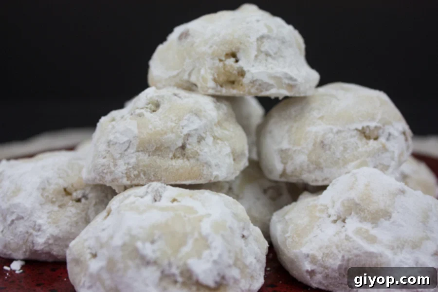 Stacked Italian Butterball Cookies, coated in powdered sugar, resting on a vibrant red plate.
