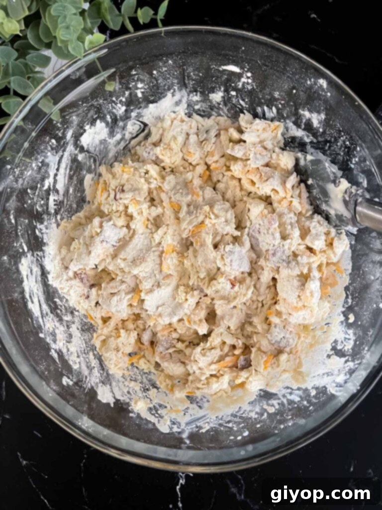 Smoky Bacon Cheddar Delights 5 Bacon cheddar biscuit dough mixed in a glass mixing bowl, showcasing a shaggy, soft texture.