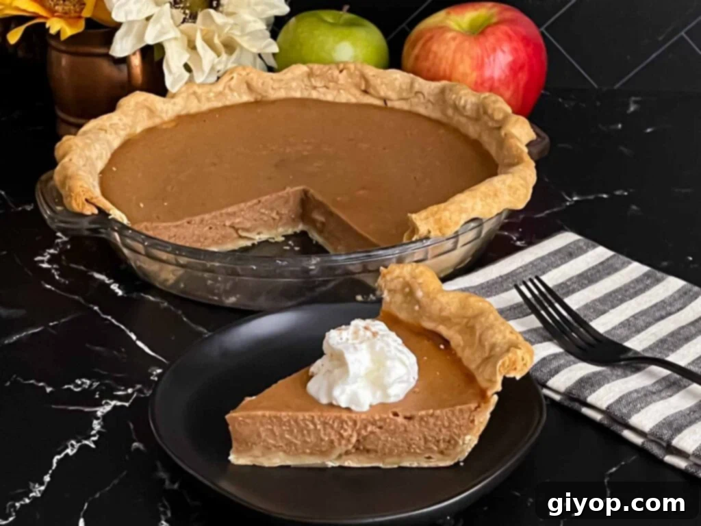 A slice of creamy Apple Butter Pie on a dark plate, beautifully garnished with a swirl of fresh whipped cream and a sprinkle of cinnamon.