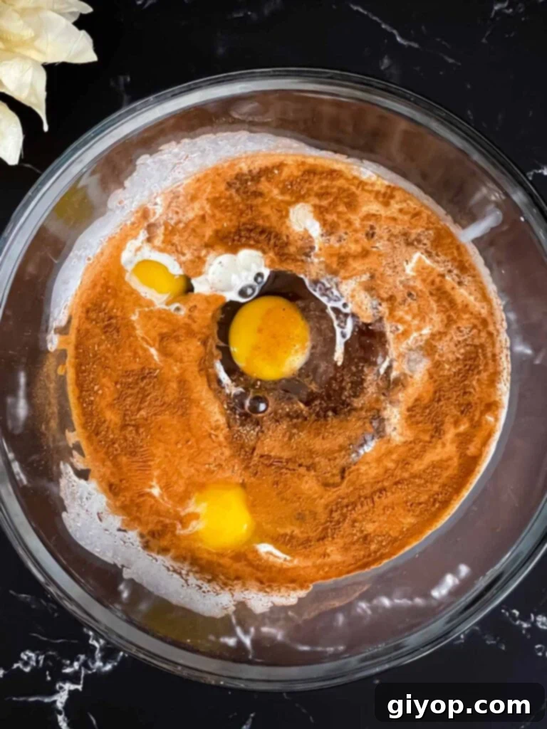 A thick, rich apple butter pie mixture in a clear glass bowl, showcasing its smooth texture before baking.