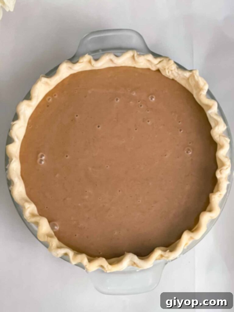 An unbaked Apple Butter Pie, with its rich, smooth filling poured into a golden pie crust, resting on a baking sheet.