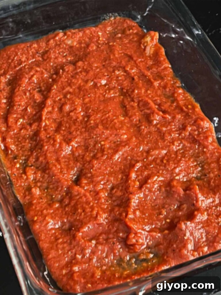 Marinara sauce spread in a 9x13 inch casserole dish.