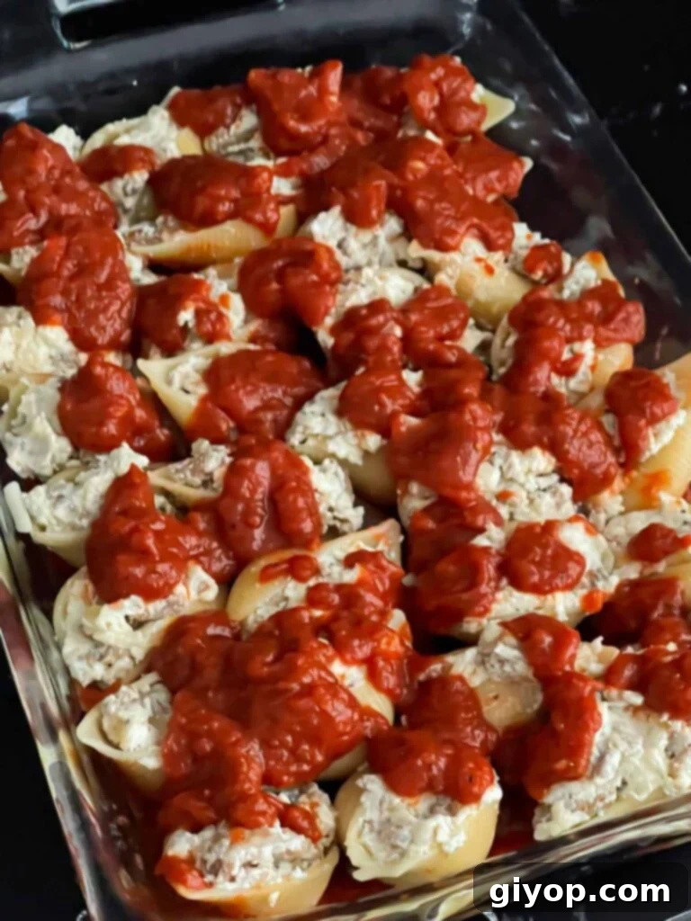 Unbaked Italian sausage stuffed shells with marinara sauce on top.