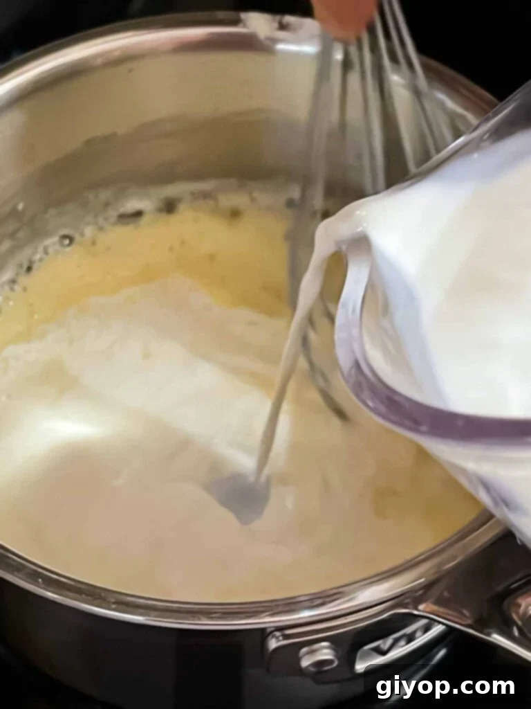 Soul-Warming Slow Cooker Chicken and Wild Rice Soup 9 Milk being added slowly to the roux for chicken and wild rice soup.